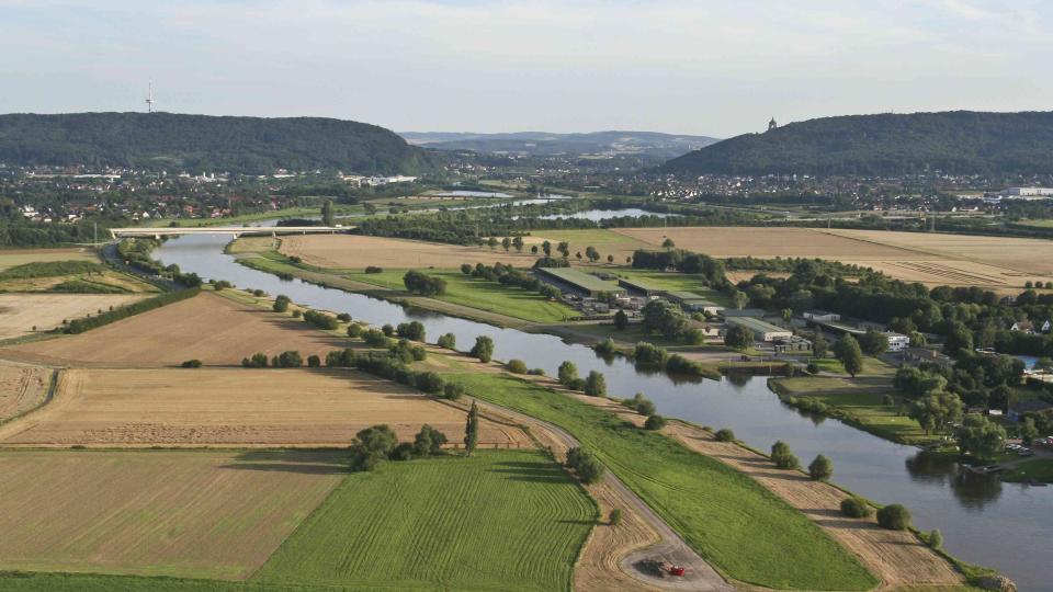 Luftbild, breiter Fluss, ebene Landschaft mit Äckern und Wiesen, Gebirgszug am Horizont