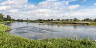Das Foto zeigt das breite Flussbett der Weser umgeben von Grünland. Der Fluss beginnt mit der Entwicklung verschiedener Uferstrukturen. Zu erkennen sind die Ausbildung kleiner Buchten und Uferabbrüche. Im Hintergrund sind Bäume zu erkennen.